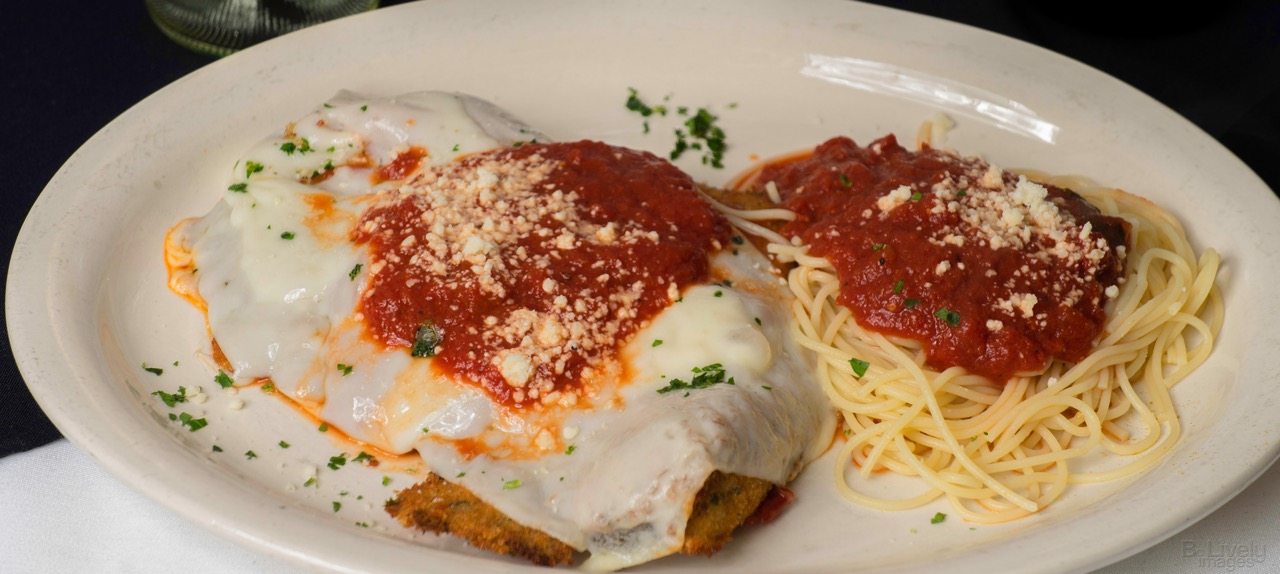 Chicken parmigiana with melted mozzarella and red sauce beside a nest of spaghettini