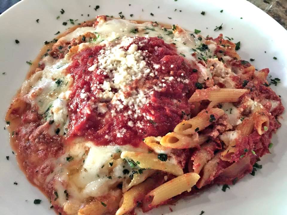Baked ziti in meat sauce with melted cheese and crumbled goat cheese
