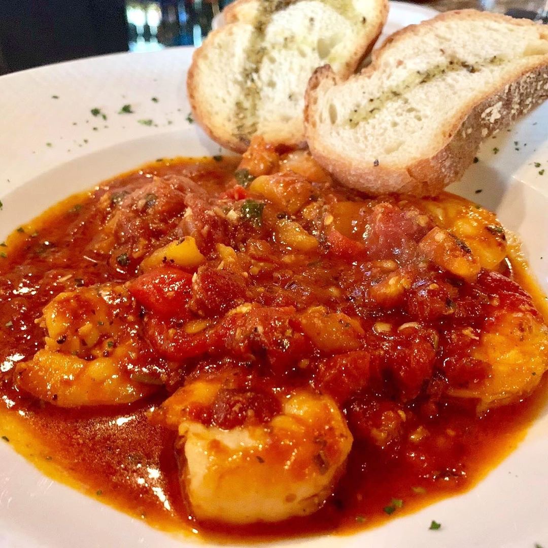 Shrimp in a chunky red tomato sauce with slices of garlic bread